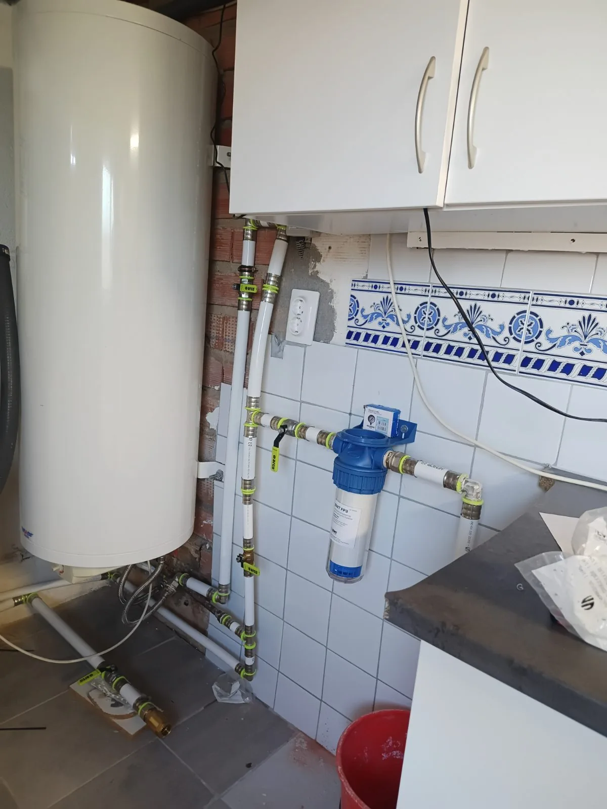 Termo eléctrico vertical conectado con tuberías multicapa y filtro de agua en un lavadero