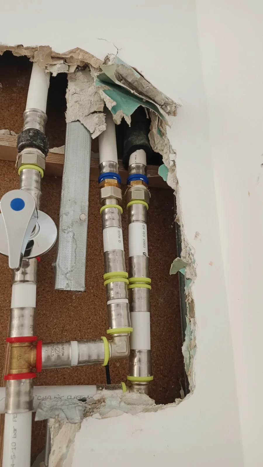 Tuberías multicapa con accesorios a presión y llave de paso en un hueco abierto de la pared