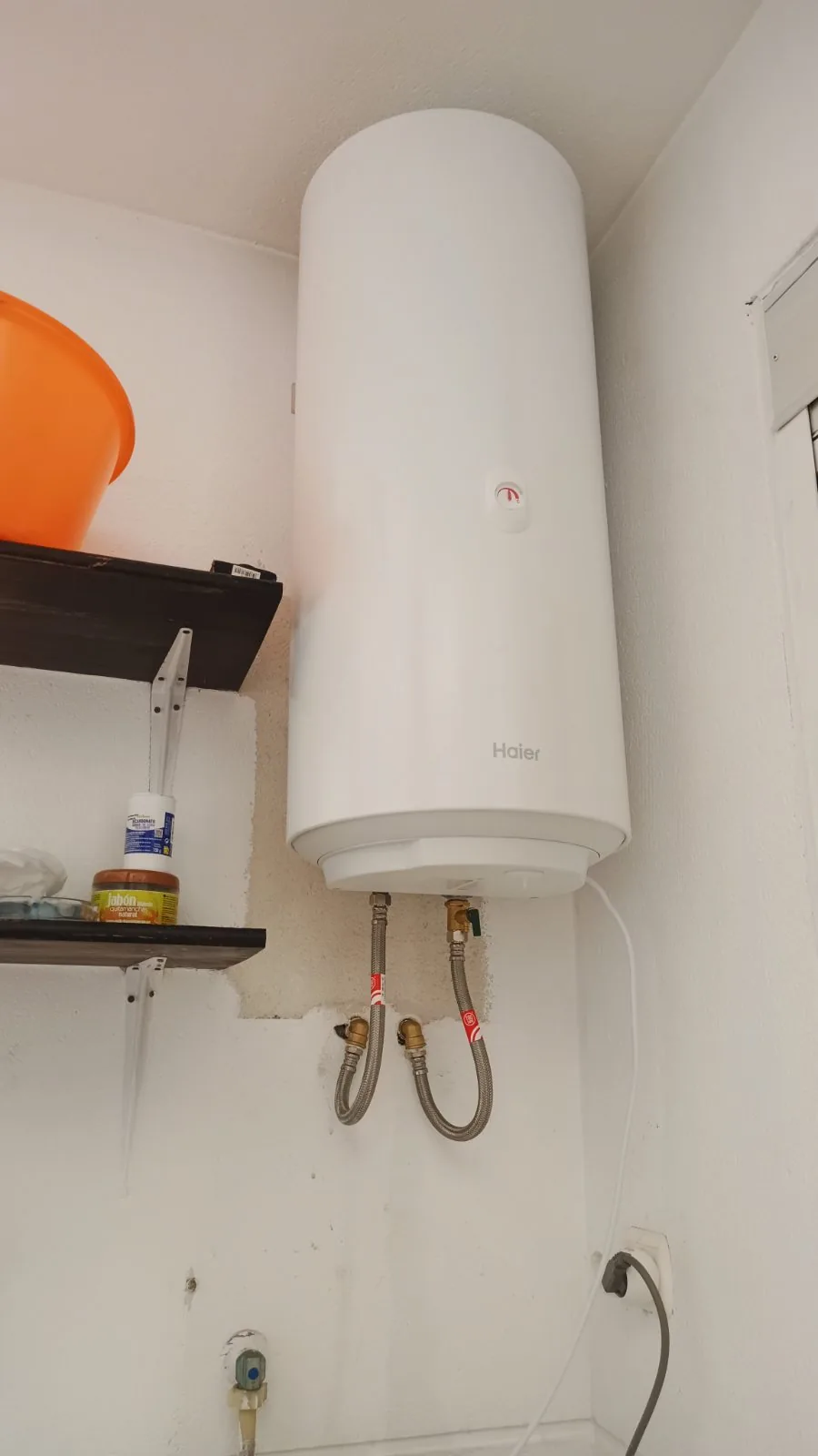 Termo eléctrico blanco colgado en la pared con flexibles de conexión