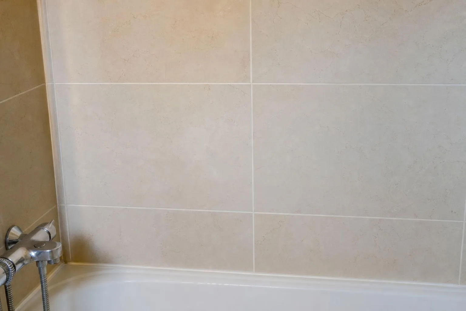 Pared reparada y pintada junto a una ducha tras arreglar una fuga
